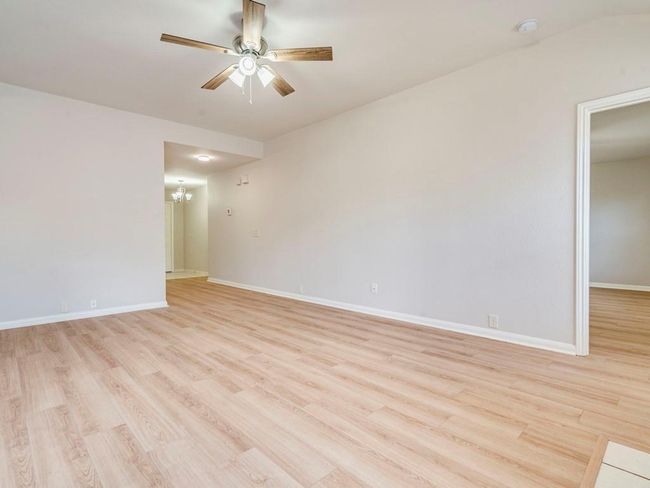 Unfurnished room featuring a chandelier, ceiling fan, and light wood-style flooring | Image 10