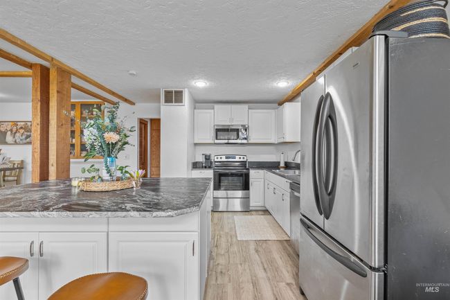 Kitchen featuring appliances with stainless steel finishes, light wood-type flooring, recessed lighting, white cabinets, and a textured ceiling | Image 5