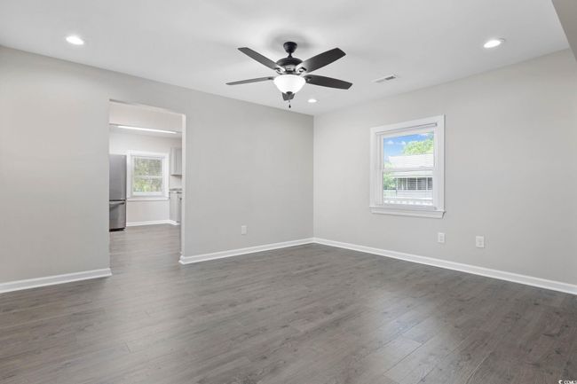 Empty room with ceiling fan, dark wood-style floors, baseboards, and recessed lighting | Image 11