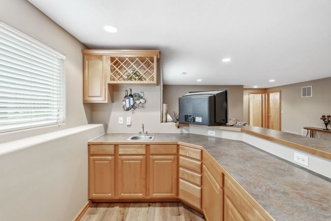 Kitchen featuring a sink, light brown cabinetry, light wood-style floors, recessed lighting, and light countertops | Image 20