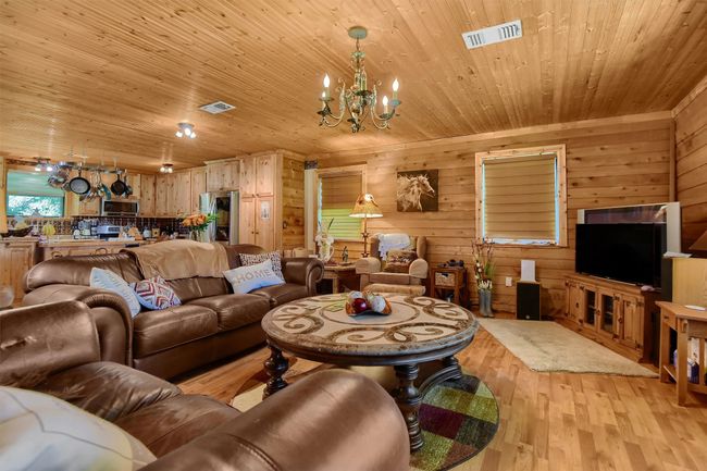 Living area with a notable chandelier, visible vents, light wood-style floors, and wooden ceiling | Image 14