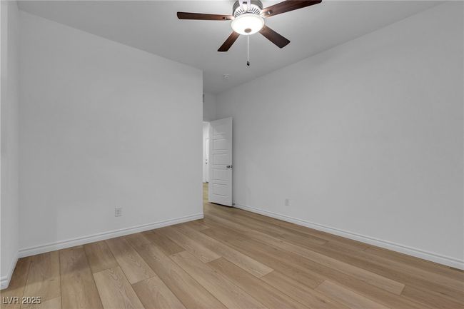 Empty room with light wood-style flooring, baseboards, and ceiling fan | Image 13