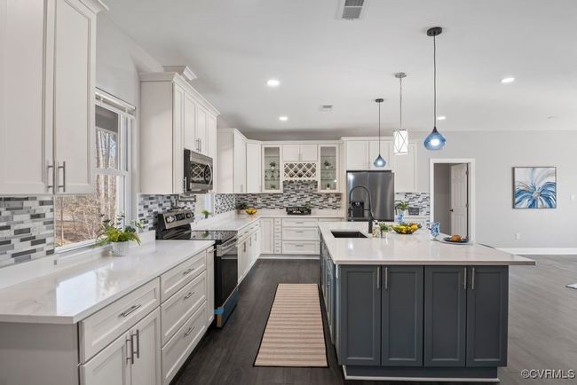 Kitchen includes stainless steel appliances, farm sink, glass insert cabinets, and white cabinetry. | Image 6