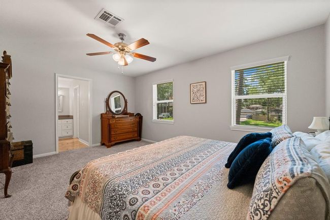Spacious bedroom features plush carpeting, and large windows offering plenty of natural light. It includes an ensuite bathroom, creating a cozy and functional space. | Image 27