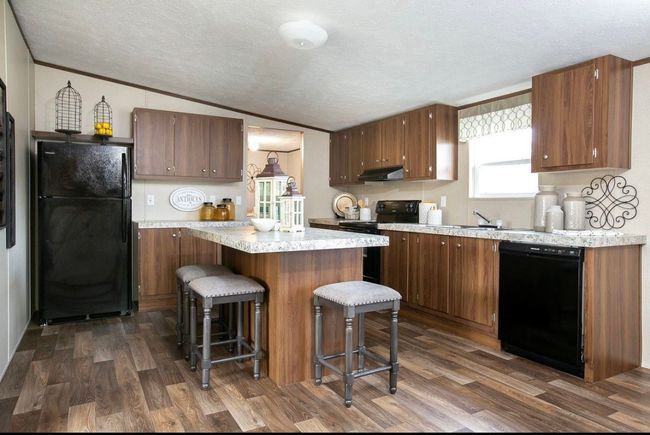 Kitchen featuring under cabinet range hood, a textured ceiling, black appliances, and dark wood-style floors | Image 7