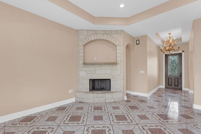 Tiled entryway with a tray ceiling, a chandelier, arched walkways, and a stone fireplace | Image 11