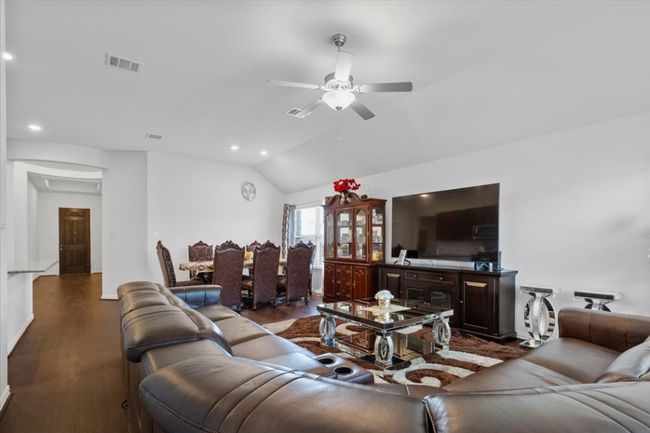 Living room featuring wood finished floors, ceiling fan, lofted ceiling, visible vents, and recessed lighting | Image 7