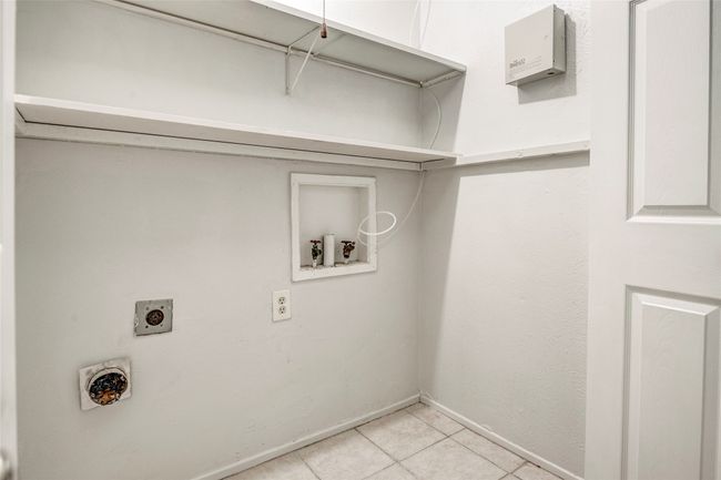 Laundry room featuring electric dryer hookup, hookup for a washing machine, light tile patterned floors, and baseboards | Image 34