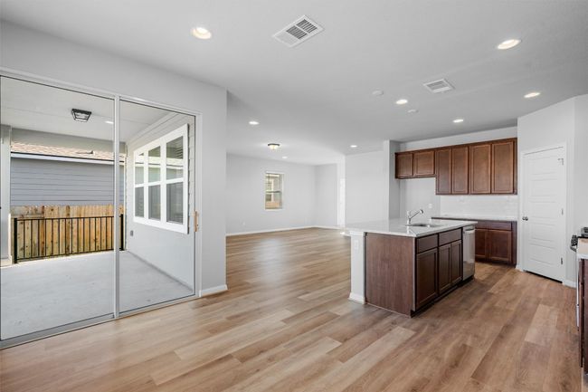 Kitchen featuring stainless steel dishwasher, recessed lighting, open floor plan, light wood finished floors, and a center island with sink | Image 14