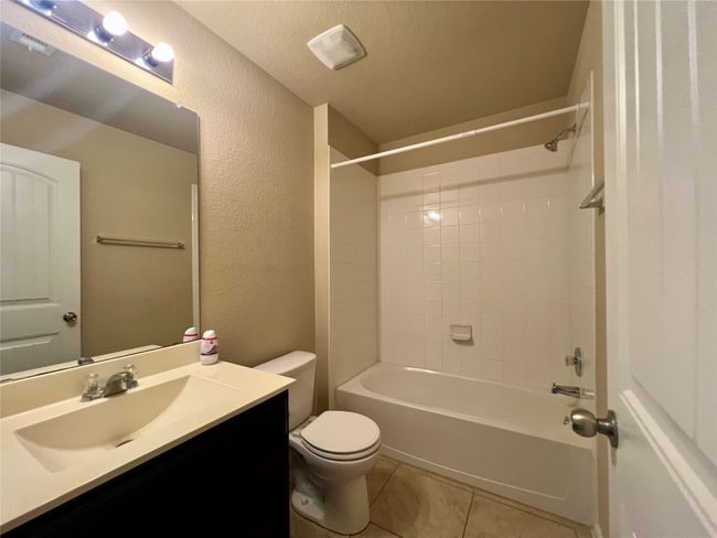 Full bathroom featuring vanity, toilet, a textured wall, shower / bath combination, and tile patterned flooring | Image 7
