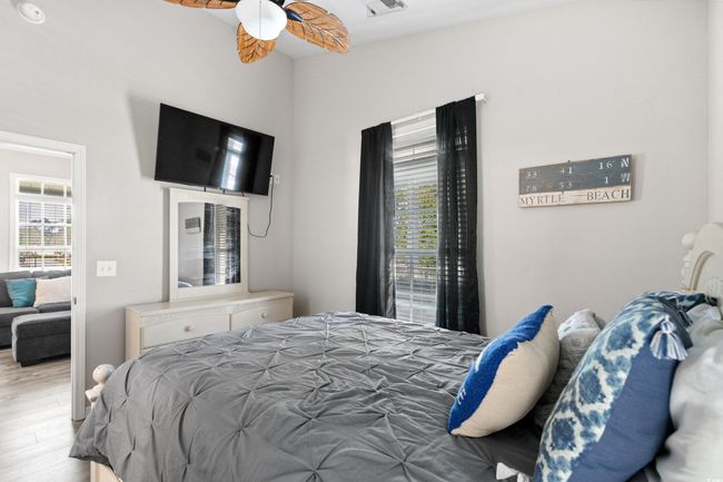Bedroom with vaulted ceiling, wood finished floors, visible vents, and baseboards | Image 29
