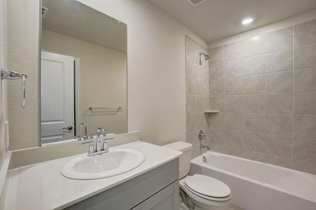 Full bath featuring shower / bathtub combination, a textured wall, and vanity | Image 15