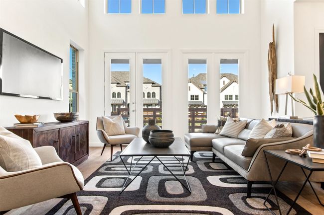 Living area with light wood-style floors, a high ceiling, and french doors | Image 11