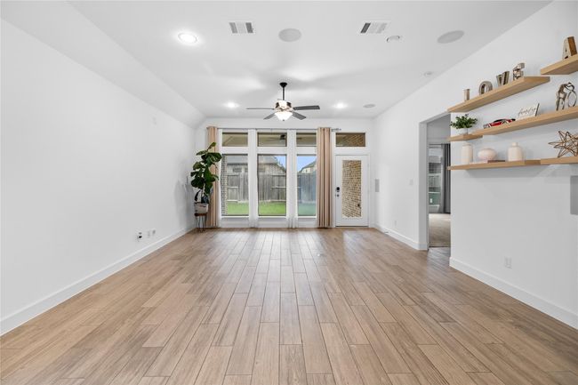 This spacious living room features tile flooring, a ceiling fan, and a built-in speaker system. Large windows offer abundant natural light. | Image 11