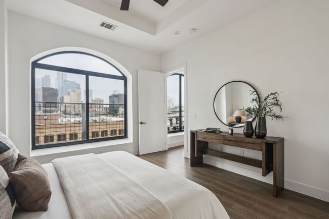 Bedroom featuring visible vents, baseboards, a raised ceiling, dark wood-style floors, and a city view | Image 11