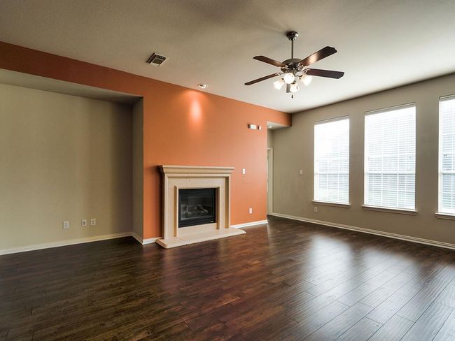 Unfurnished living room featuring ceiling fan, wood finished floors, a glass covered fireplace, and baseboards | Image 26