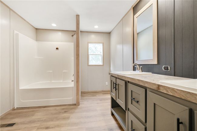 Bathroom featuring a sink, double vanity, visible vents, shower / bathing tub combination, and wood finished floors | Image 23