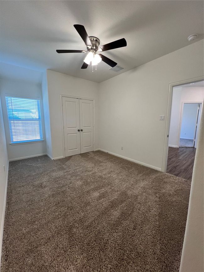 Unfurnished bedroom with dark carpet, a closet, and ceiling fan | Image 26
