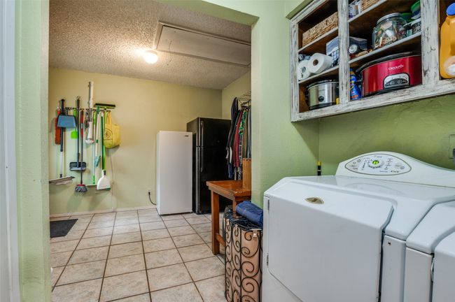 Washroom with laundry area, attic access, a textured ceiling, light tile patterned floors, and washer and clothes dryer | Image 23