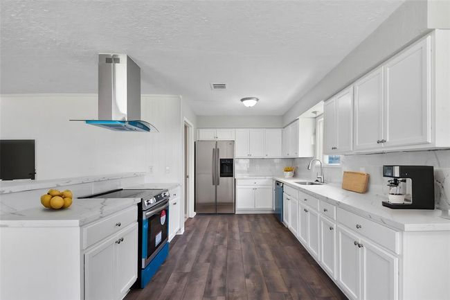 The kitchen with stone countertops, offering both elegance and durability. With ample cabinet space and brand-new appliances, it combines style and functionality to create the perfect cooking environment. | Image 12