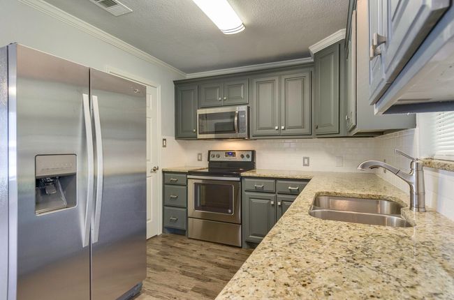 Kitchen featuring appliances with stainless steel finishes, dark wood finished floors, ornamental molding, backsplash, and light stone counters | Image 13