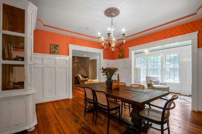 Dining space with wallpapered walls, a chandelier, wood-type flooring, a wainscoted wall, and a decorative wall | Image 8