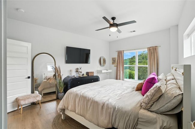Bedroom featuring multiple windows, wood finished floors, and a ceiling fan | Image 16