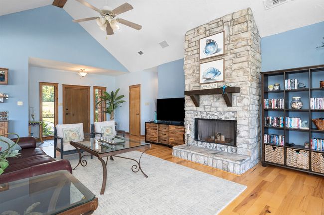 Living room with high vaulted ceiling, light wood-type flooring, ceiling fan, and a fireplace | Image 8