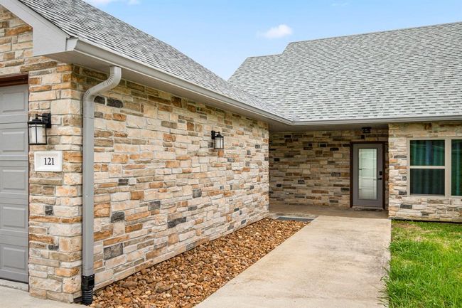 Home offers a stone exterior, full gutters & newer roof. | Image 3