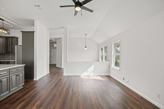Unfurnished living room featuring ceiling fan, dark wood finished floors, and vaulted ceiling | Image 7