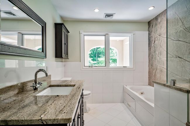 Bathroom featuring visible vents, tile walls, and a tub with jets | Image 14