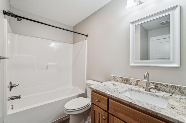 Full bathroom with LVP flooring, birch cabinet and granite vanity top. | Image 22