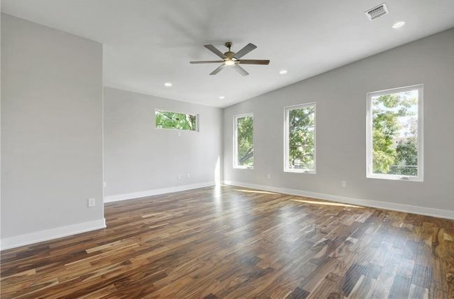 Empty room featuring a ceiling fan, baseboards, visible vents, and wood finished floors | Image 26