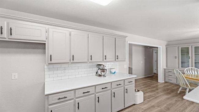Kitchen with white cabinets, light wood-type flooring, light countertops, and decorative backsplash | Image 35
