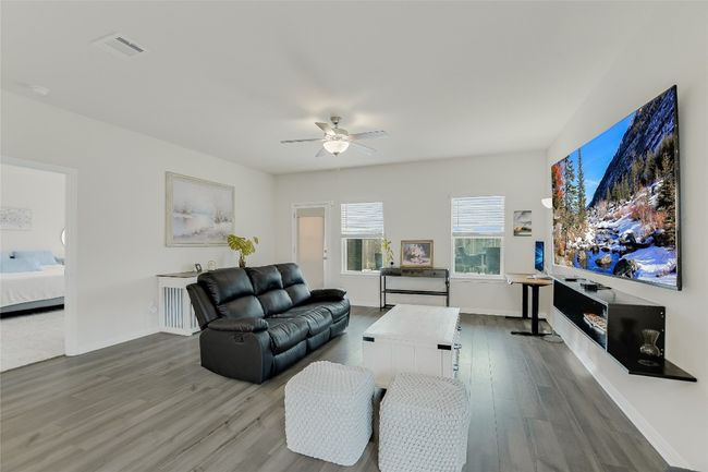 Living area with wood finished floors, a ceiling fan, and baseboards | Image 13