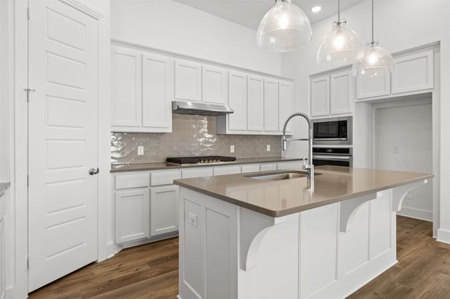 Kitchen featuring a sink, appliances with stainless steel finishes, under cabinet range hood, decorative backsplash, and dark wood-style flooring | Image 8