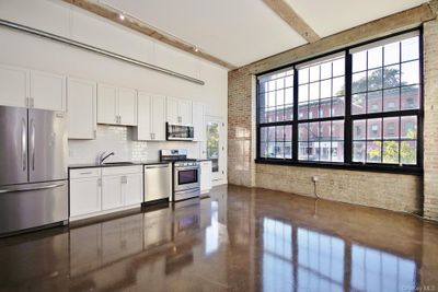 Kitchen featuring brick wall, appliances with stainless steel finishes, and beam ceiling | Image 2