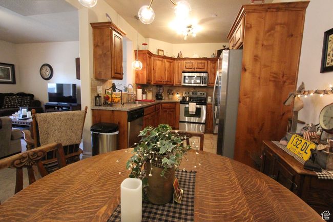 Kitchen featuring stainless steel appliances, a sink, open floor plan, backsplash, and brown cabinets | Image 6