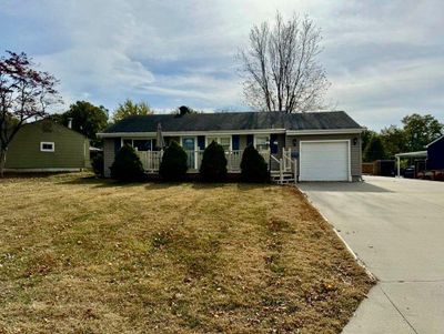 Ranch-style house with a carport, a front yard, and a garage | Image 1