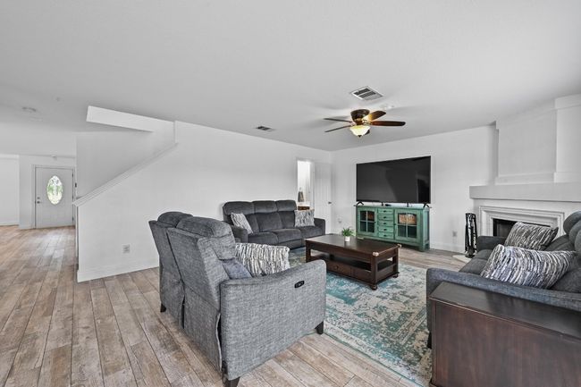 Living area with ceiling fan, a fireplace, light wood-type flooring, and baseboards | Image 9