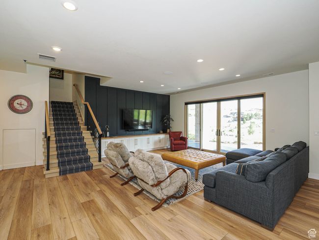 Living area with light wood-style flooring, stairway, and recessed lighting | Image 65