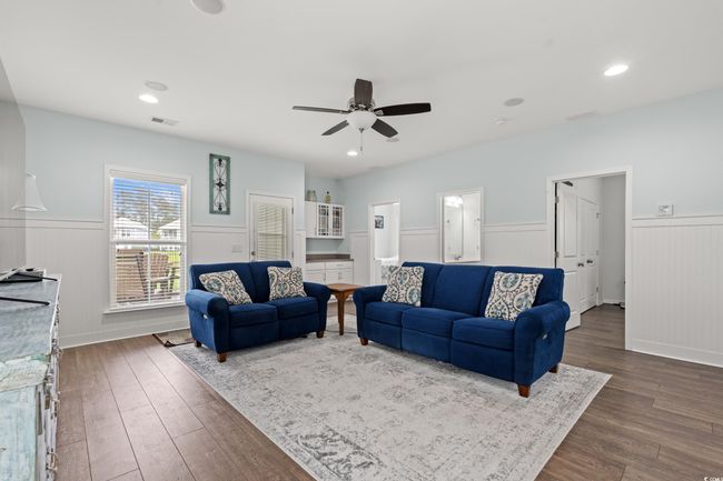 Living area on the first level featuring wainscoting, wet bar, speaker system, recessed lighting and an elevator. | Image 8