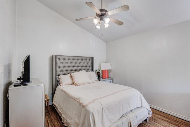 Bedroom with a ceiling fan, baseboards, lofted ceiling, and wood finished floors | Image 4
