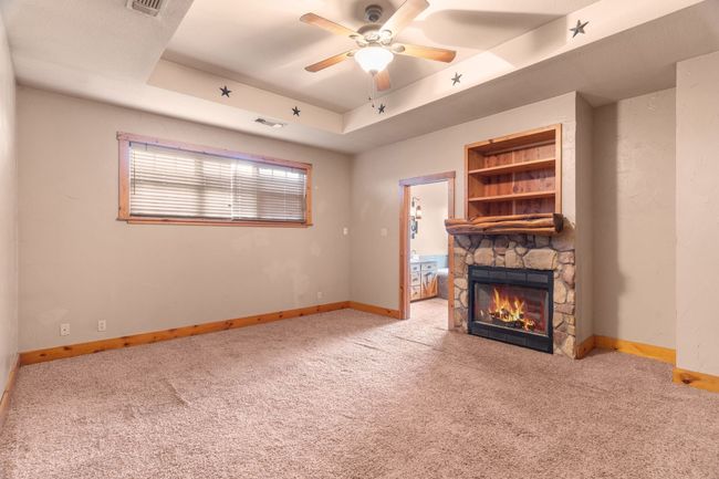 Unfurnished living room featuring visible vents, a stone fireplace, a raised ceiling, and carpet floors | Image 34