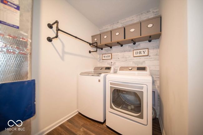 clothes washing area with dark vinyl flooring with wood appearance and baseboards | Image 23