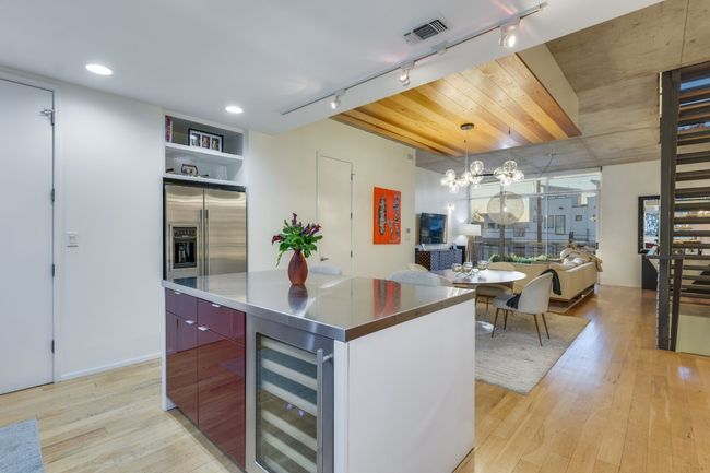 Kitchen featuring wine cooler, rail lighting, stainless steel counters, a large island, and light hardwood / wood-style floors | Image 17