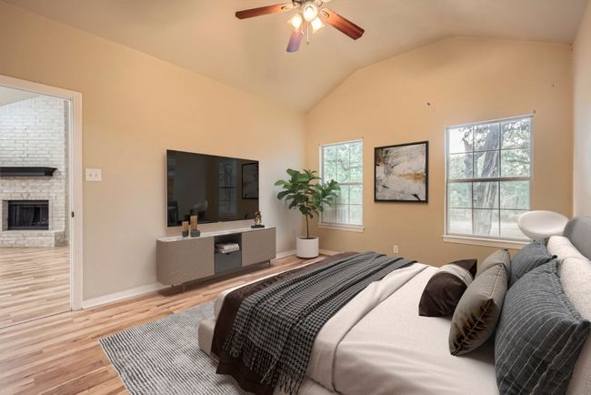 Bedroom with vaulted ceiling, light wood-style flooring, a fireplace, baseboards, and ceiling fan | Image 9