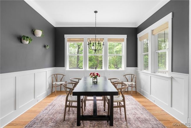 Dining space featuring plenty of natural light, wainscoting, crown molding, a chandelier, and light wood finished floors | Image 15