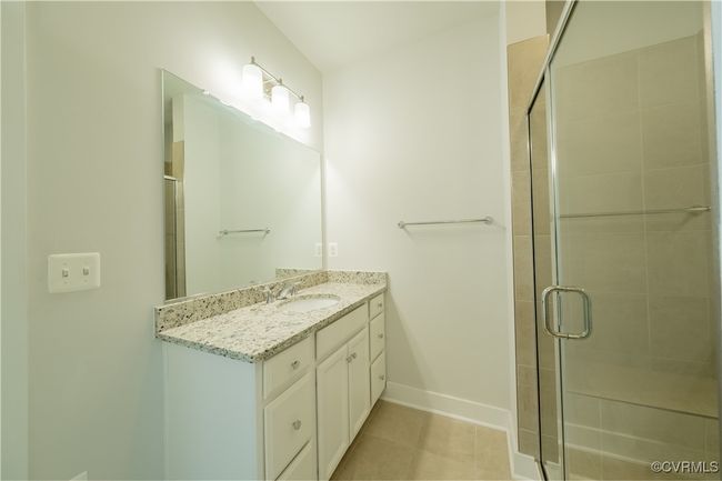 Bathroom with vanity, a shower stall, baseboards, and tile patterned floors | Image 37