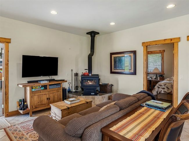 Living room with a wood stove and light tile patterned floors | Image 18